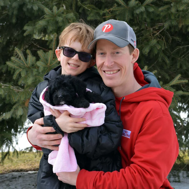 Family holding a small black puppy